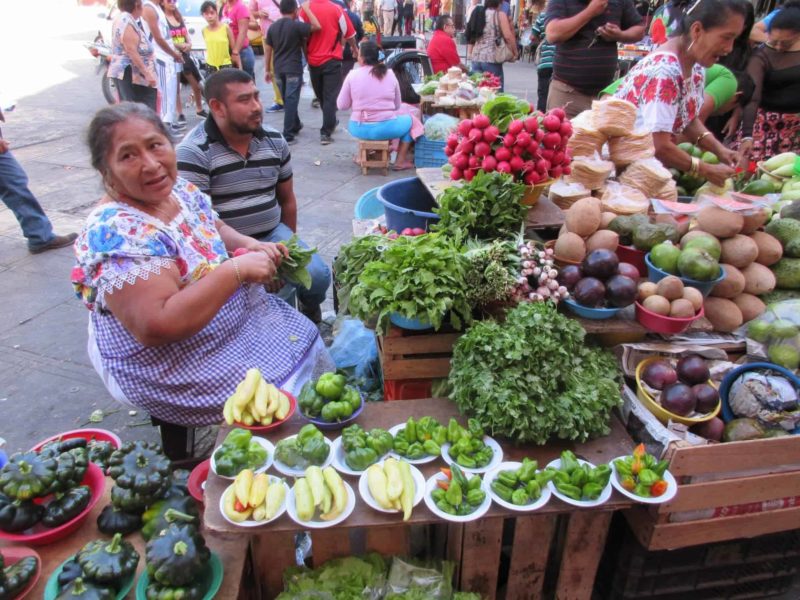 market lady in the Yucatan selling vegetables and wearing a traditional Mexican embroidered dress