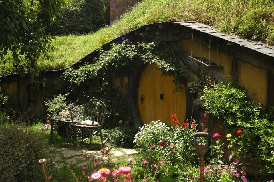 a beautiful fairy garden in Ireland a tiny little house with a moss covered roof and lots of flowers