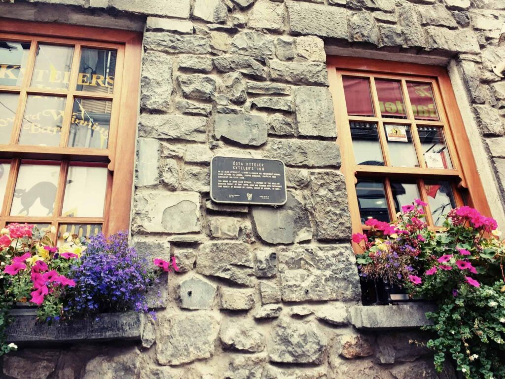 Kytelers Inn in Kilkenny an ancient stone building with flower boxes and a sign commemorating Alice the witch