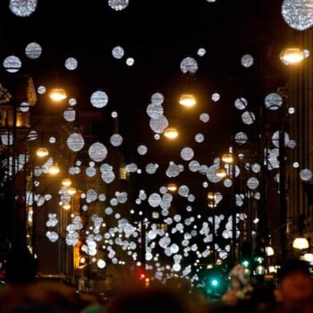 The Christmas lights of oxford street. The lights are small balls almost like planets hanging over the streets while shoppers run in and out of the stores