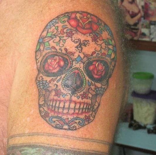 sugar skull tattoo in full colour with roses in the eye sockets