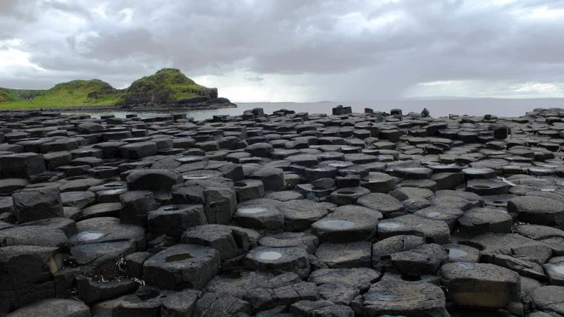 Giants Causeway the hexagonal shaped black and grey pillars of the causeway with the North sea in the background and the hills of Antrim