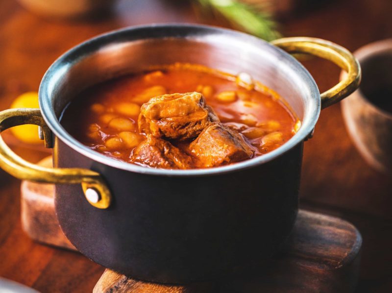 A pot of stew with boxty, Ireland potato pancake, and Irish potato cake on a wooden table.