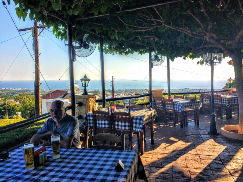 Dining on mezes in Cyprus. Blue and white checked tablecloths and a straw roof of the restaurant. With stunning views out to the sea