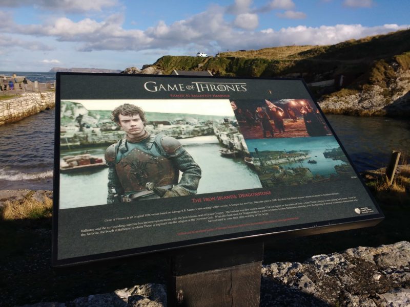 Visiting the Dark Hedges in N. Ireland where the wood came from for the Game of Thrones doors. An information plaque stands with a photo of Theon Greyjoy at Ballintoy Harbour