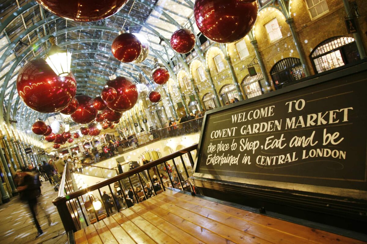 Christmas Lights Display in Covent Garden Market, people present, in London. The modern colourful Christmas lights attract and encourage people to the market.