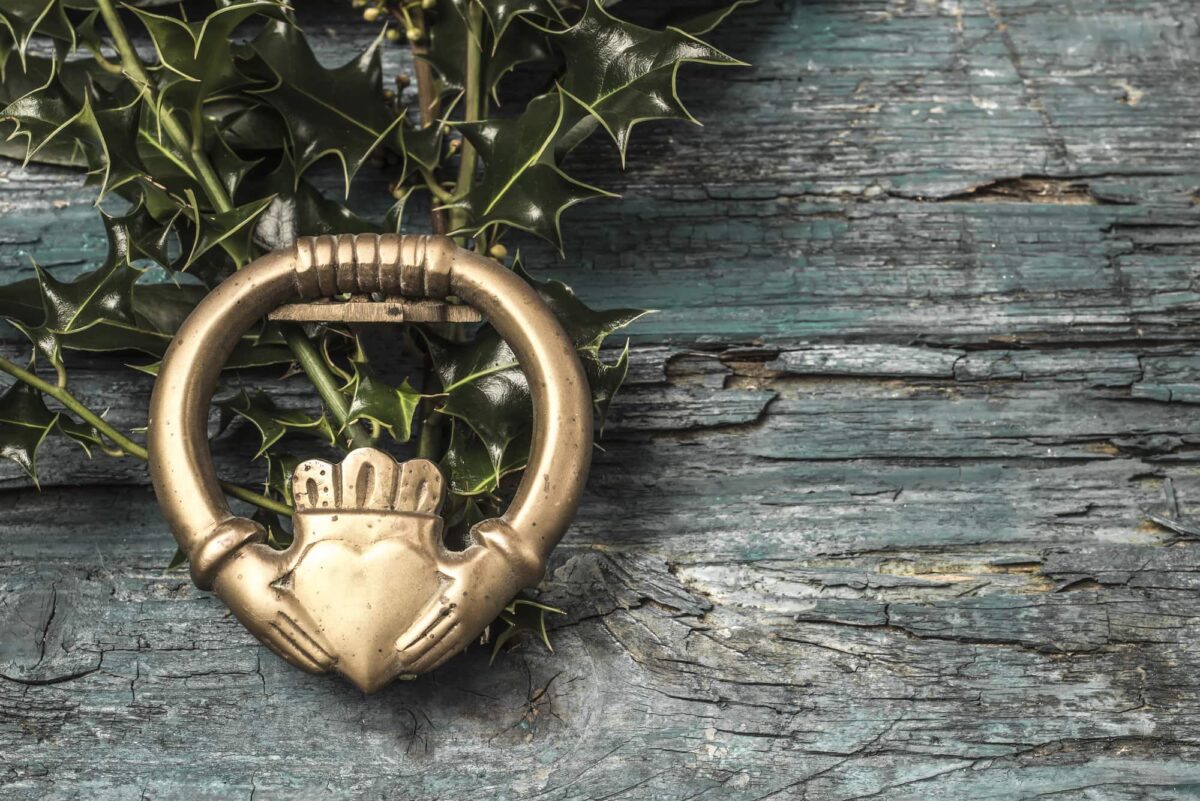 Claddagh and holly branches irish symbol of love, friendship and loyalty in old wooden background