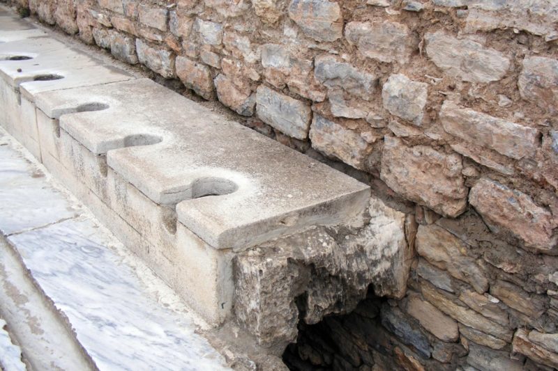 The toilets used at Ephesus, look remarkably similar to today's versions with a key shaped hole cut in a slab of marble to sit on and a row of these along a wall with a trench underneath them