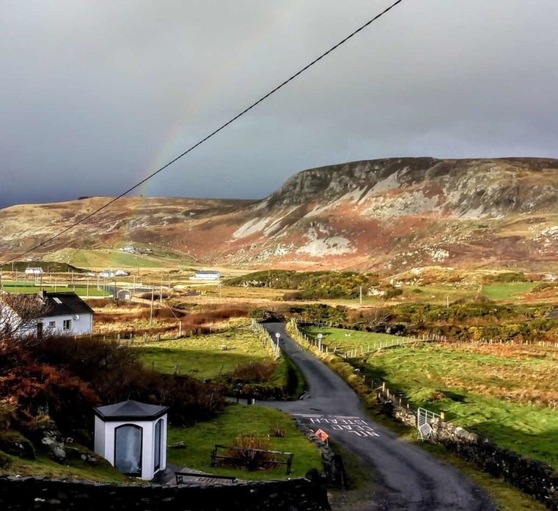 view of the hills of Glencolmcille in Donegal Ireland with a rainbow over the hills