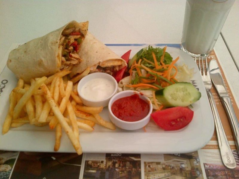 a plate full of beautiful Turkish food a falafel wrap and chips and various dips