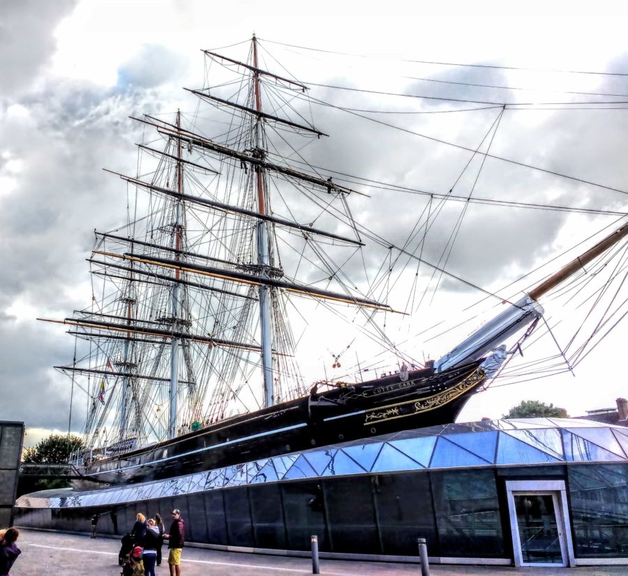 The Cutty Sark Greenwich London - a shot of the whole ship sitting on its raised platform in Greenwich. You can see the glass visitors centre from which the ship rises up out of of. There are no sails on the ship but you can see the hundreds of ropes and wires for the riggin. 