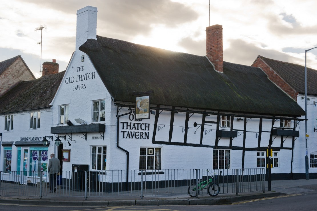The medieval white tip tilty building of the Old Thatch Tavern with its half-timbered exterior and thatch roofed