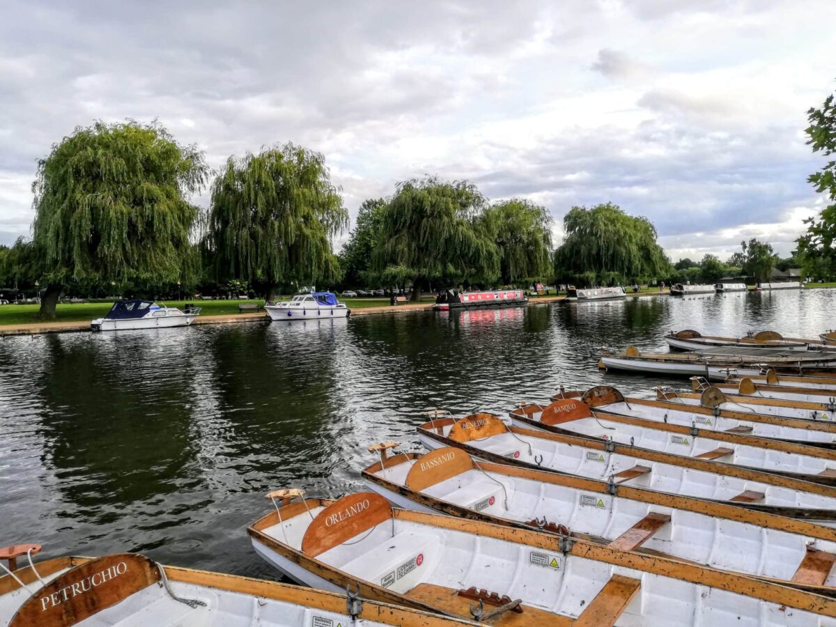 Row Boats you can rent on the River Avon in Stratford upon Avon. The river banks have several boats parked along the shore line of the river bank which has many willow trees