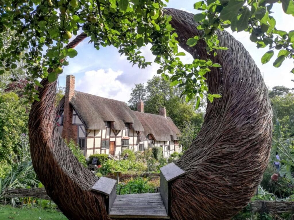 Anne Hathaway's cottage on the outskirts of Stratford Upon Avon. A dramatically curved willow seat frames the old thatched cottage where Shakespeare's wife lived as a child