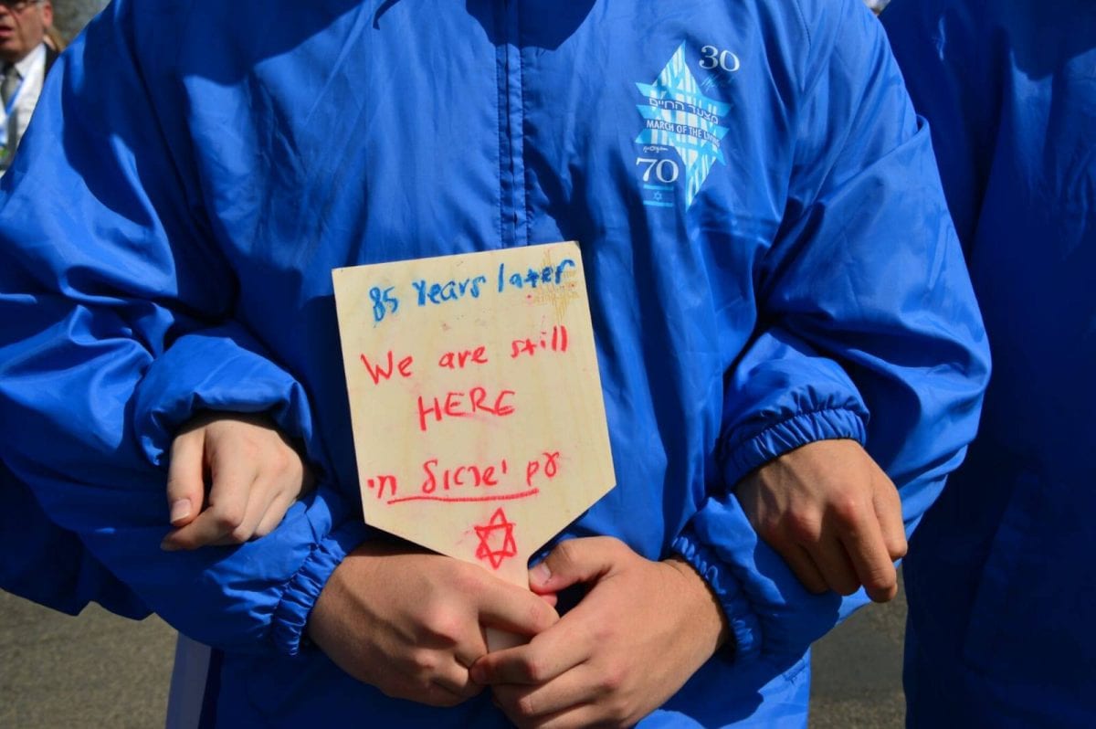 young man holding a sign saying we are still here the March of the Living at Auschwitze - Birkenau 