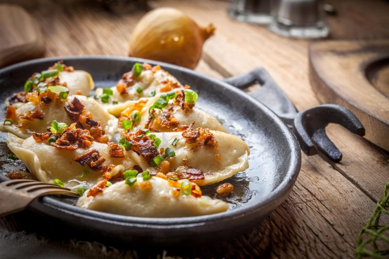 Dumplings with meat, onions and bacon on a cast iron skillet.  