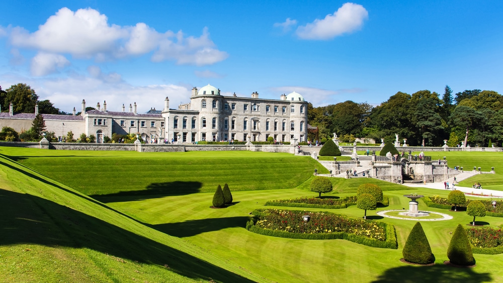 Day trips from Dublin. Grand historic mansion north of Dublin with ornate gardens and sculpted green lawns under a bright blue sky.