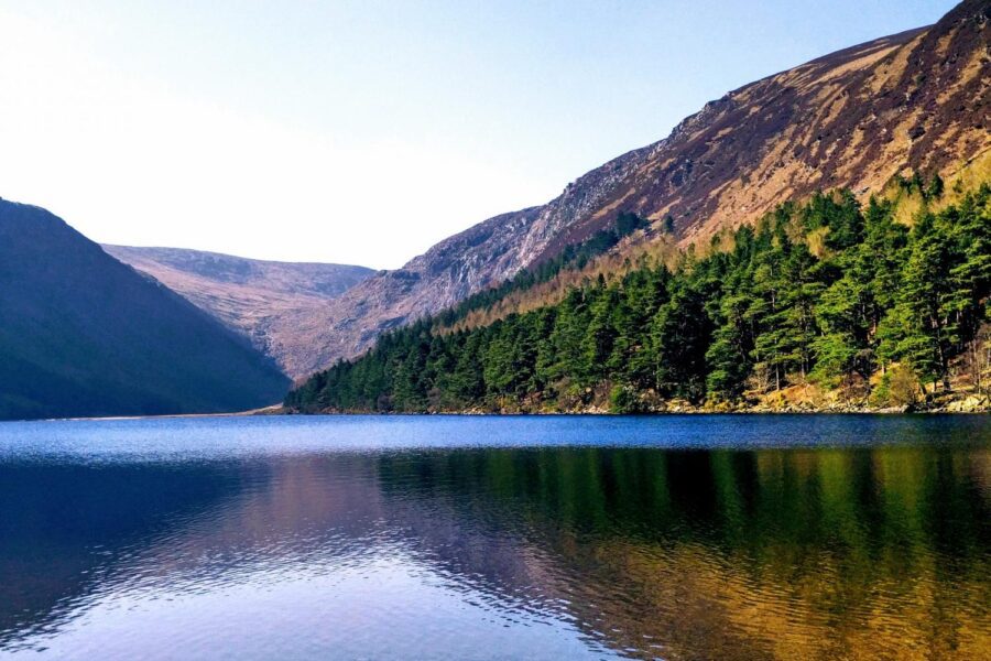 the Upper Lake of Glendalough Ireland rippling waters shows the mirror image of the mountains of Wicklow rising above the blue lake
