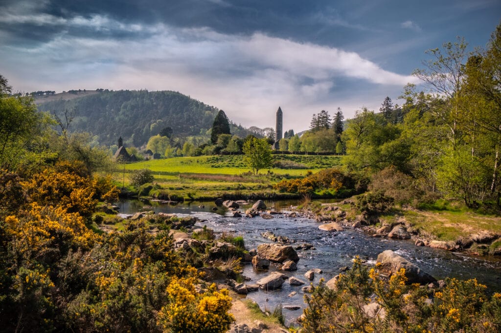 Glendalough Ireland in the Wicklow mountains a view of the ancient monastic site in the background with the mountains rising above it and the river in front