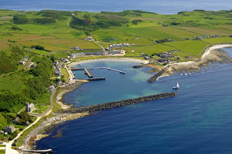 Rathlin Island harbour from a drone showing the pier and the small row of houses that are on the island