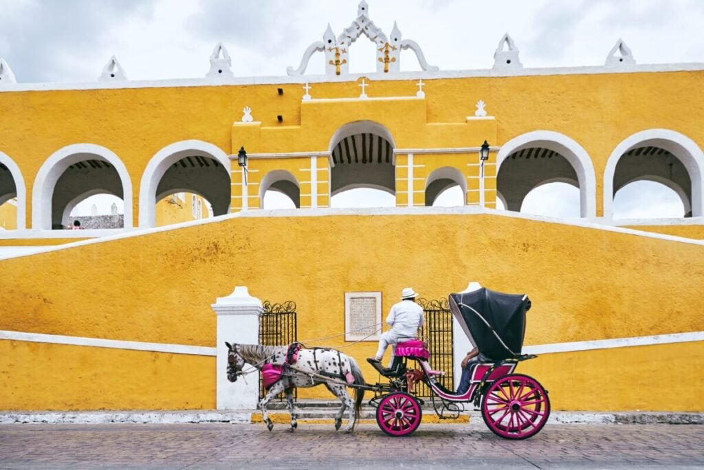 The horse and buggies of Izamal in the Yucatan. A horse and buggy sits in front of one of the golden buildings of the city