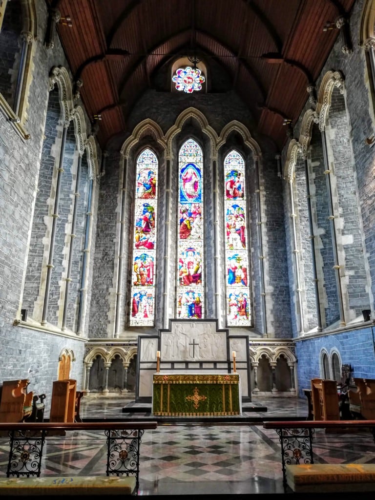 interior of St. Canice's Cathedral with the stained glass windows and rose window above the altar.