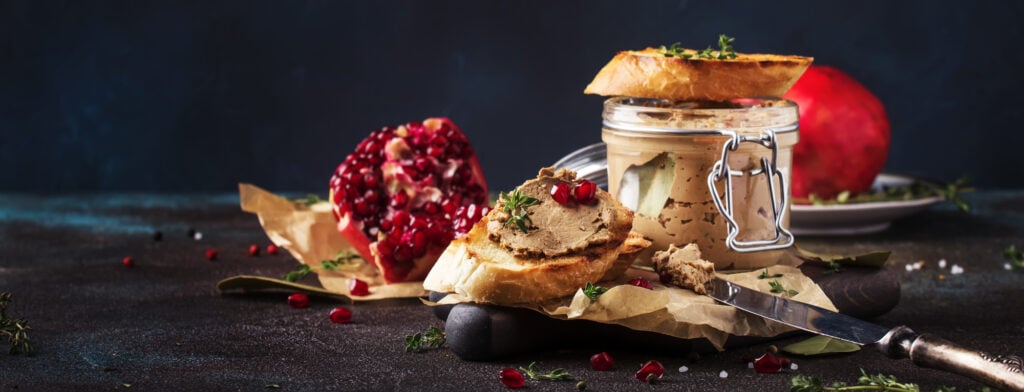 Meat liver pate on toasted bread with fruit seeds and spice herb, brown kitchen table, copy space, 