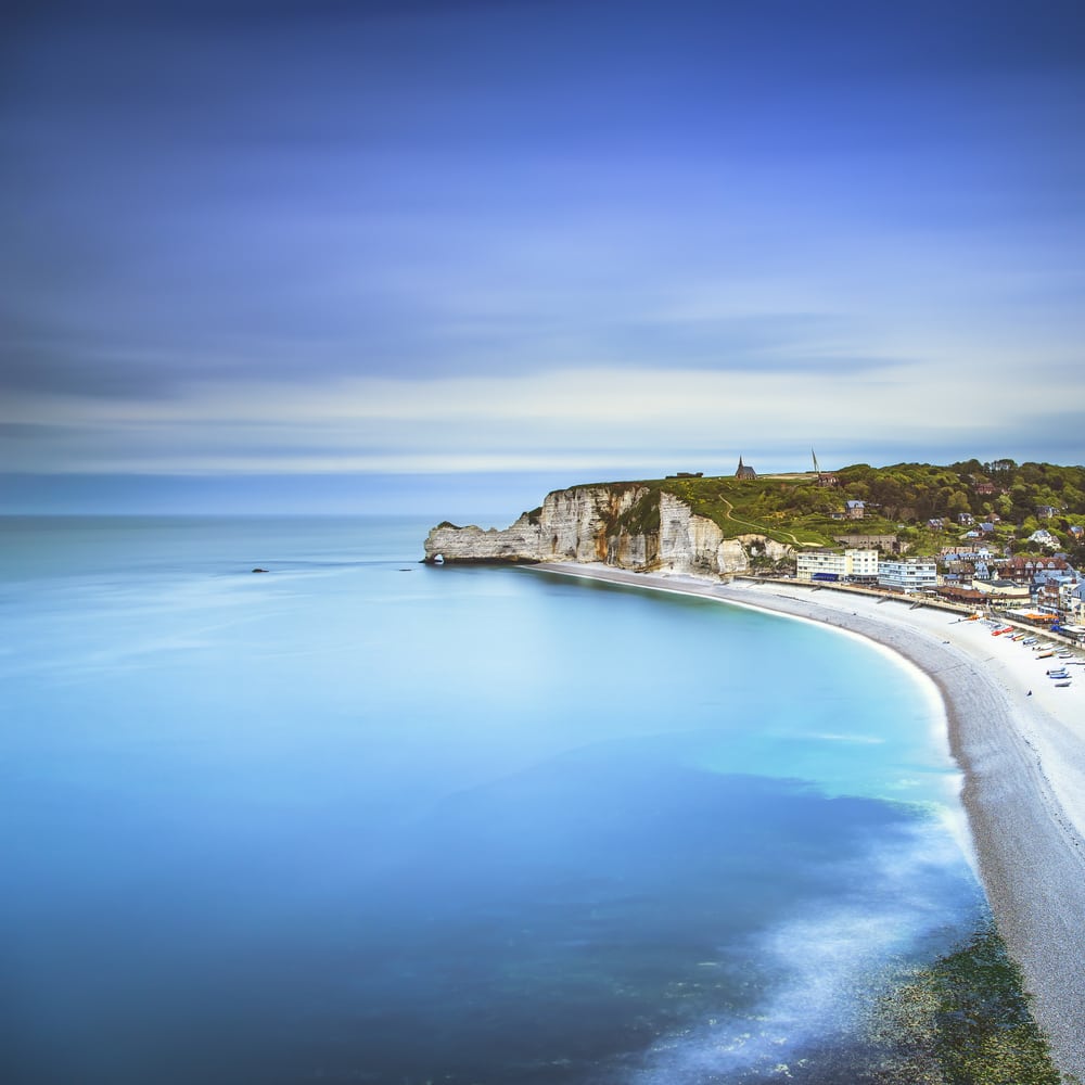 Etretat cliff, rocks, natural arch landmark and blue ocean. Most Beautiful Towns and Villages in Normandy
