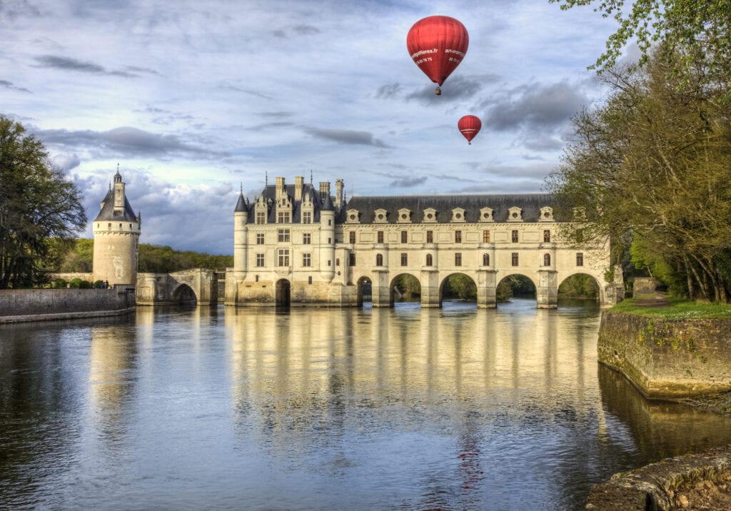Chenonceaux, France- April 6, 2014: Two red hot air balloons fly above the Chenonceau Castle spanning the river Cher in the Loire Valley ,France.