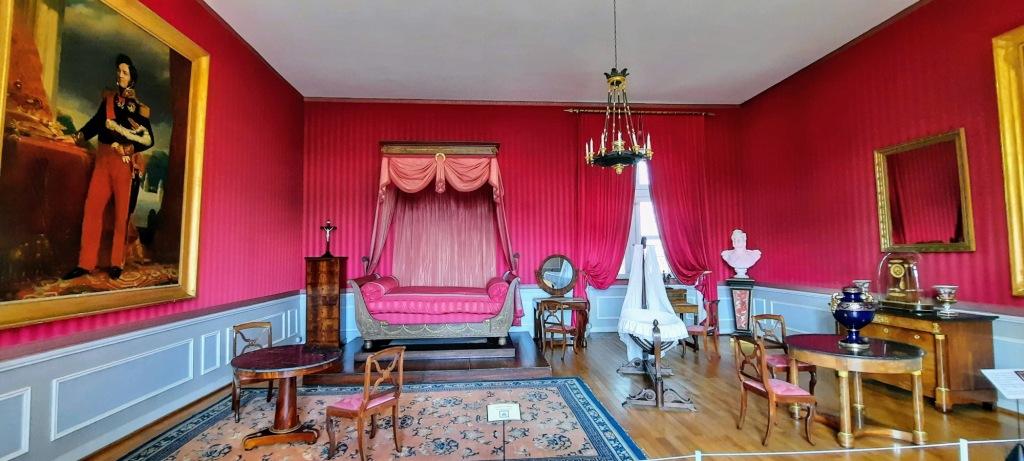 Red wallpapared bedroom at teh Chateau Amboise. There is a Curtained daybed at teh end of the room