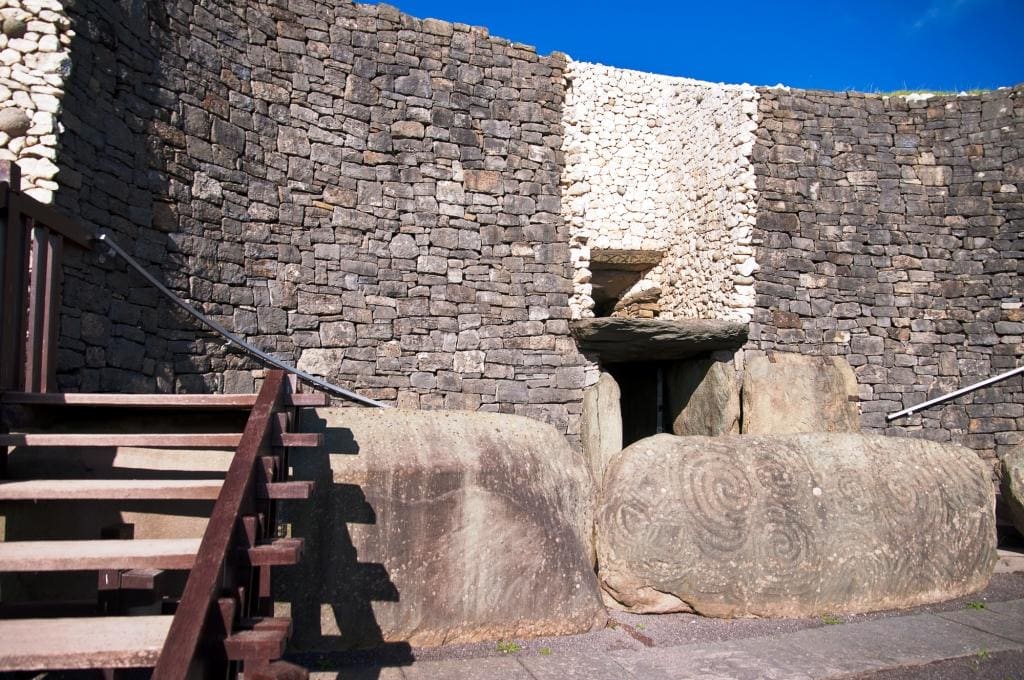 Newgrange passage tomb entrance there are steps into the tomb and the doorway is covered by a large rock carved with spirasl