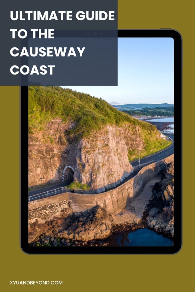 Aerial view of a coastal road winding through cliffs, featured in a travel guide for the Causeway Coastal Route.