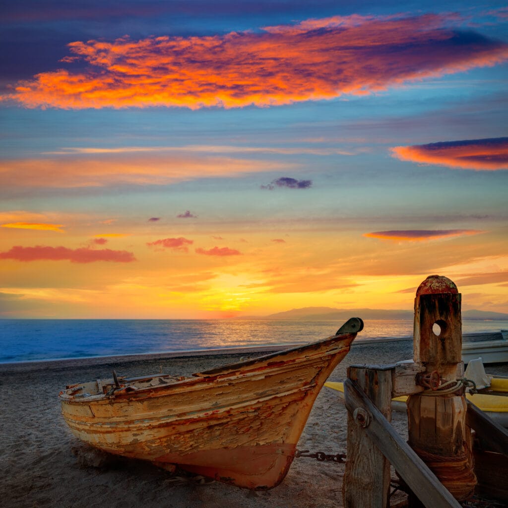 Almeria holidays: Things to do in Almeria Spain a beautiful sunset view of the Costa Alermia Spain and an old rowboat sitting on the beach