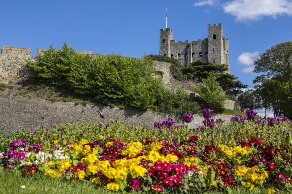 A view of Rochester Castle with beautiful flowers in the foreground, in the historic city of Rochester in Kent, UK