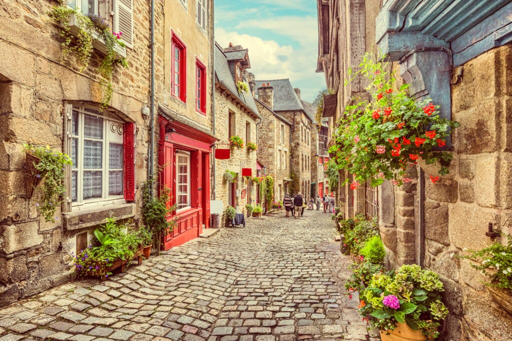 Beautiful view of scenic narrow alley in Dinan France with historic traditional houses and cobbled street in an old town in Europe with blue sky and clouds in summer 