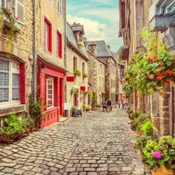 Beautiful view of scenic narrow alley with historic traditional houses and cobbled street in an old town in Europe with blue sky and clouds in summer