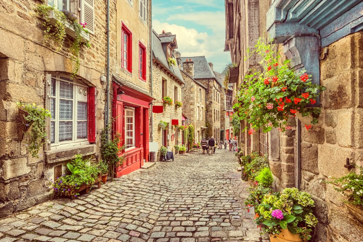 Beautiful view of scenic narrow alley with historic traditional houses and cobbled street in an old town in Europe with blue sky and clouds in summer