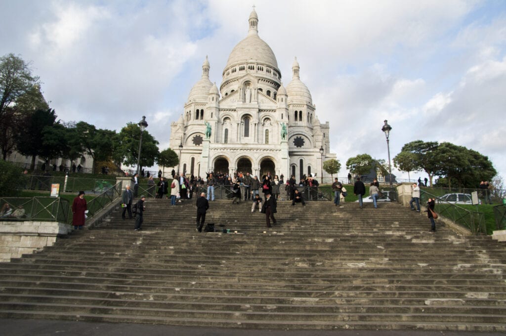tourists visit the Sacre Coeur Church (Basilica of the Sacred Heart) at the summit of Montmartre Hill, the highest point in the city of Paris, France
