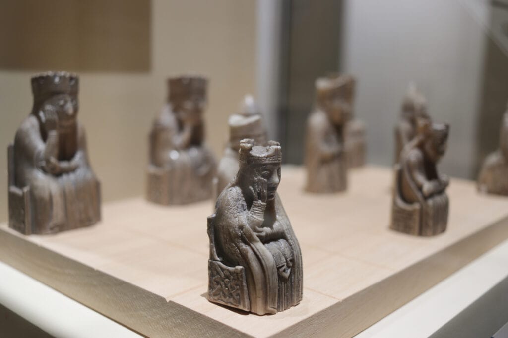 The Lewes Chessmen are made of ivory and some are exhibited in the National Museum of Scotland. They were also used in the Harry Potter film. Shown is the queen figure with other figures in the background.