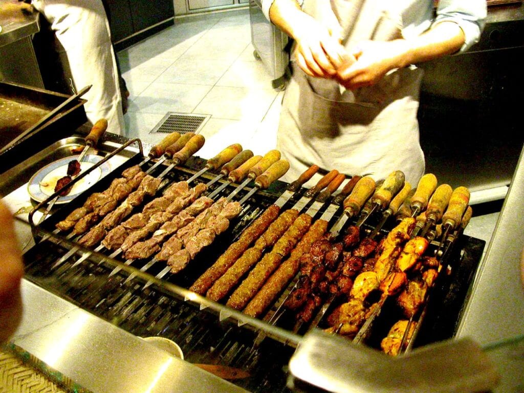 A man is preparing Turkish food on a grill.
