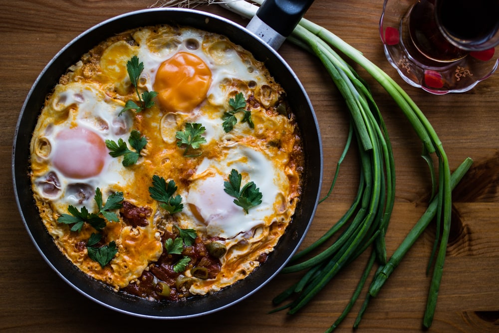 Menemen is a traditional Turkish dish which includes eggs, tomato, green peppers, and spices such as ground black pepper, ground red pepper, salt and oregano.