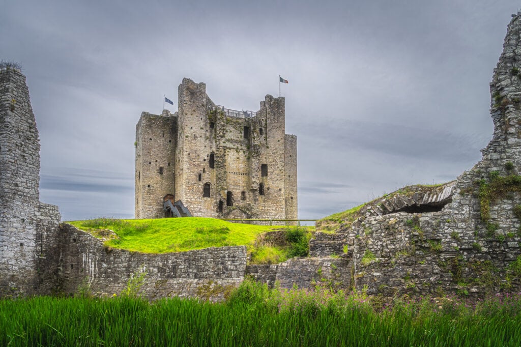 View on Trim Castle through a gap between fortification walls with dark moody sky in Trim village, County Meath, Ireland