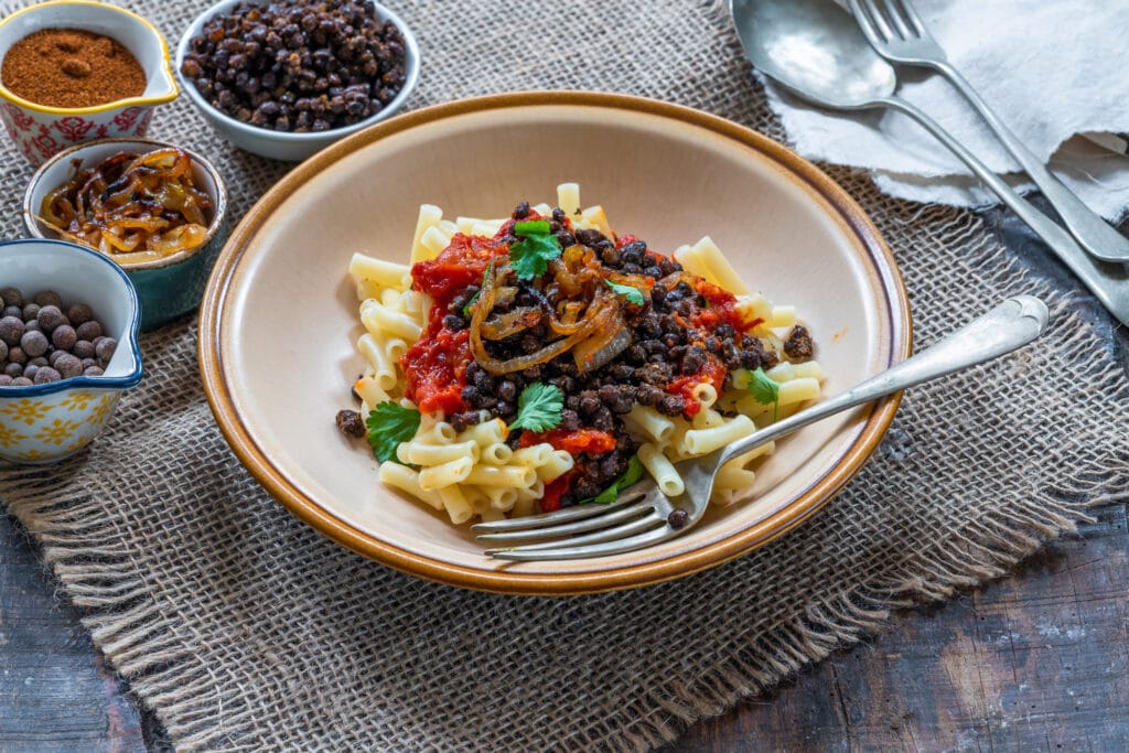 Kushari - Egyptian vegetarian dish with lentils, spiced tomato sauce and macaroni topped with fried onions