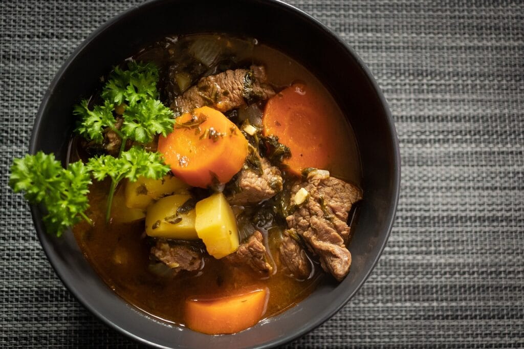 A bowl of national beef stew with carrots and parsley.