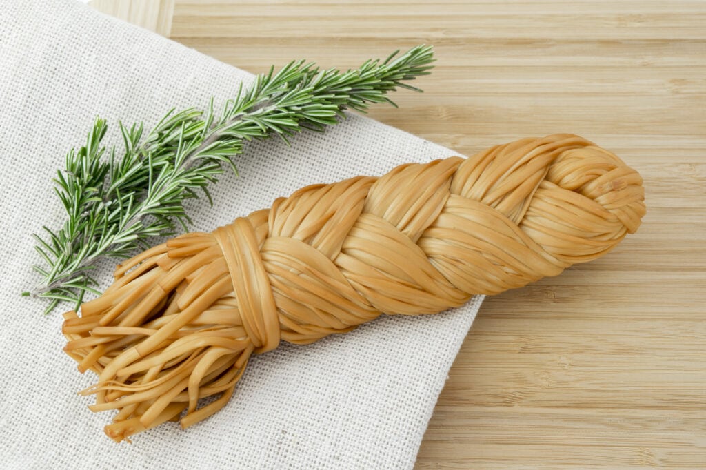 An armenian food - a strand of pasta with a rosemary sprig on a napkin.