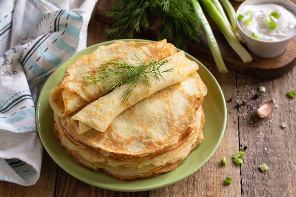 Potato pancakes, not sweet, served with garlic cream sauce on rustic wooden table.