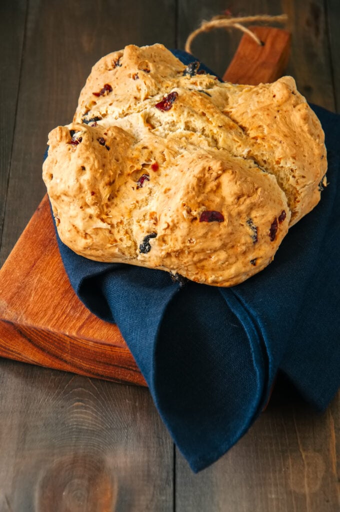 Homemade cranberry raisin and walnut Irish soda bread on a wooden board. Wooden background.