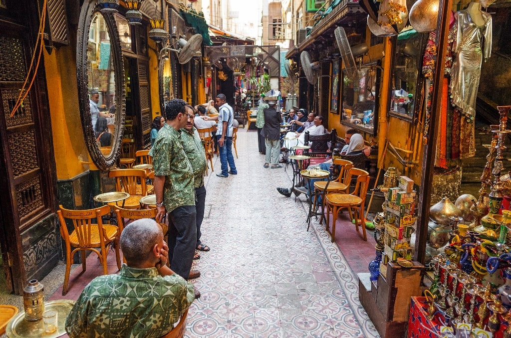 A cafe serving traditional Egyptian foods in the Khan el Khalili bazaar. small tables with trays of mint tea and colourful hookash line the street