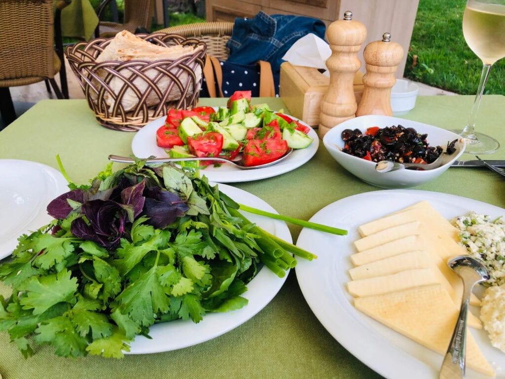 A table with plates of Armenian food and a glass of wine.