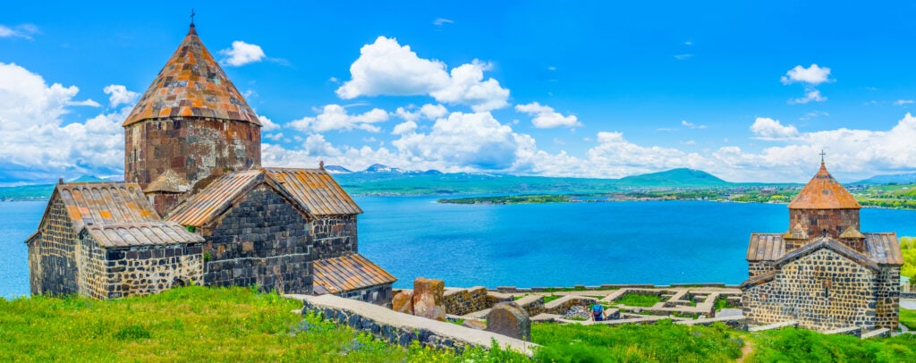 A church on top of a hill with views overlooking a lake, where visitors can also enjoy delicious Armenian food.